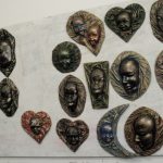 Wiszące na ścianie metalowe maski wykonane przez osadzonych w Zakładzie Karnym w Tarnowie-Mościcach