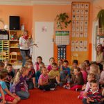 Prezes koła "Paidagogos" Marta Falińska wśród siedzących na dywanie dzieci w sali zabaw