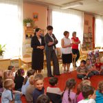 Kanclerz, wicekanclerz i dyrektor przedszkola wśród siedzących na dywanie dzieci w sali zabaw