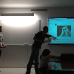 Troje studentów w sali lekcyjnej podczas prezentowania multimedialnego projektu