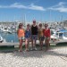 Five students standing on the quay. In the background of moored boats