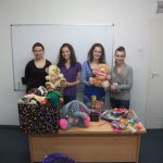 Cztery studentki pozują z misiami pluszowymi na biurku zebrane zabawki i artykuły biurowe