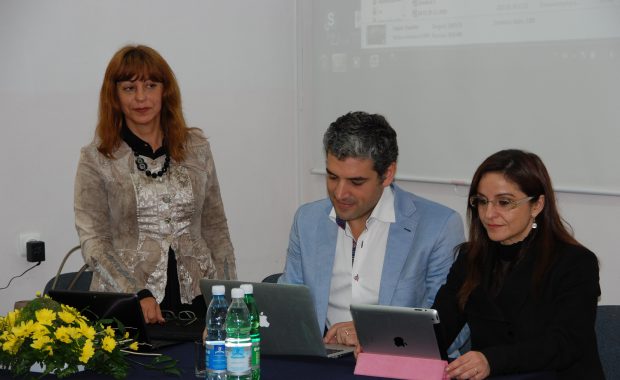 Dwie kobiety i mężczyzna - przedstawiciele uczelni na Maderze - przy biurku w sali wykładowej