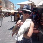 Dziewczyna na ulicy Rodos z białą papugą na ramieniu