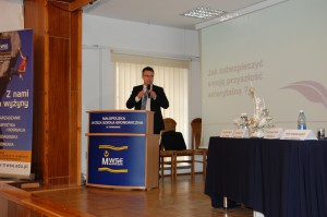 mgr Tomasz Szybalski z Open Finance stoi przy mównicy prowadząc prezentację o sposobach oszczędzania