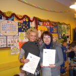 Wychowawczyni mgr Wiesława Krysa oraz mgr Marta Falińska stoją w klasie, prezentując dyplomy