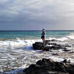 Studentka stoi na kamieniach na plaży, wokół ocean