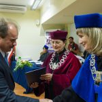 Kanclerz i dziekan Smoleń wręczają dyplom studentowi
