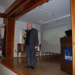 Rektor prof. Michał Woźniak stoi na scenie auli i wita zebranych