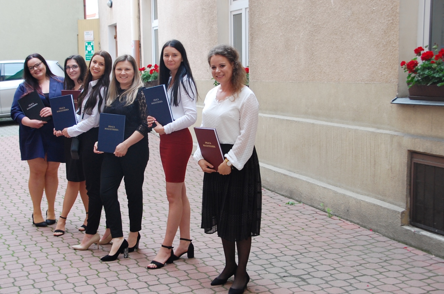 Grupa studentek po egzaminie dyplomowych na dziedzińcu budynku MWSE